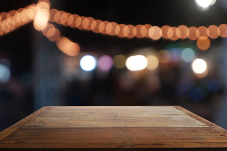 Empty wooden table in front of abstract blurred night light in c