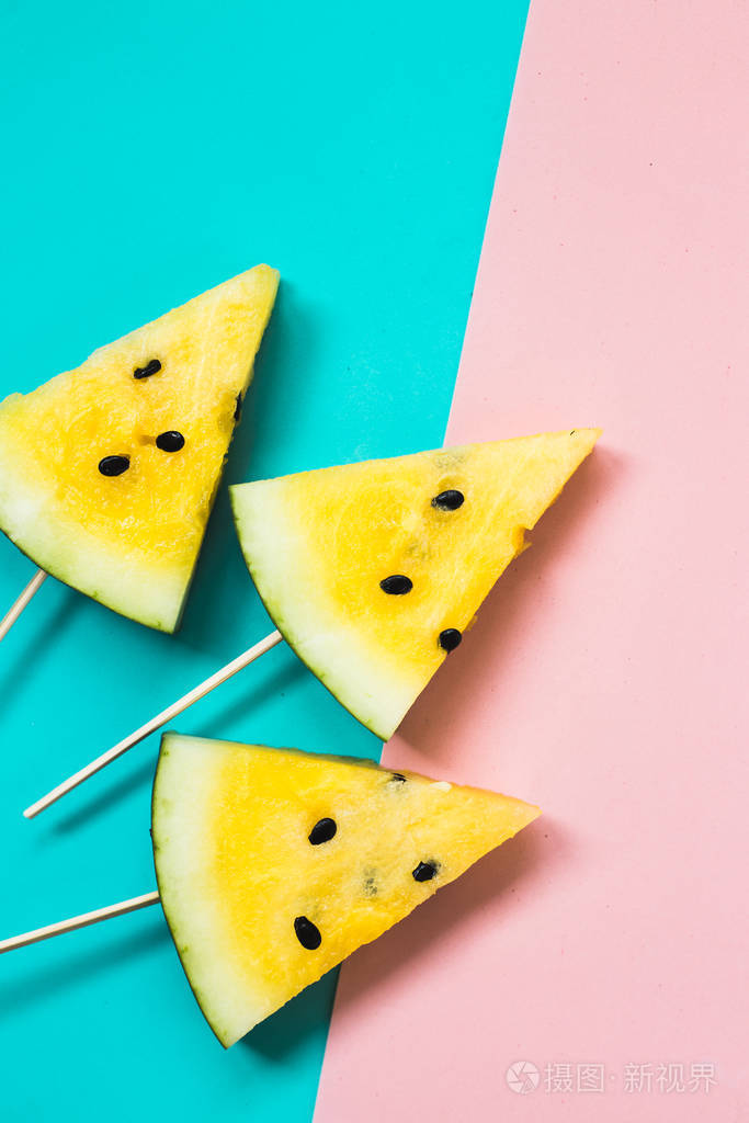在粉蓝色的背景上切下三角形的熟黄色西瓜片