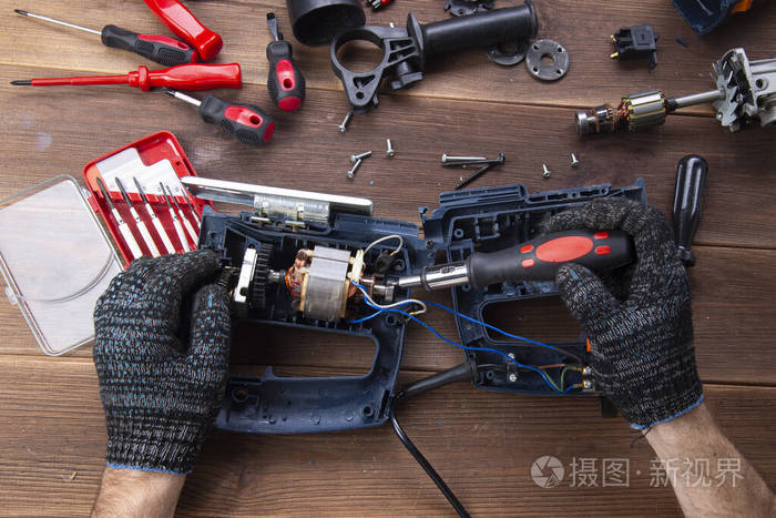 主人修理一个坏了的电器钻头木桌上的切割机电动工具修理厂