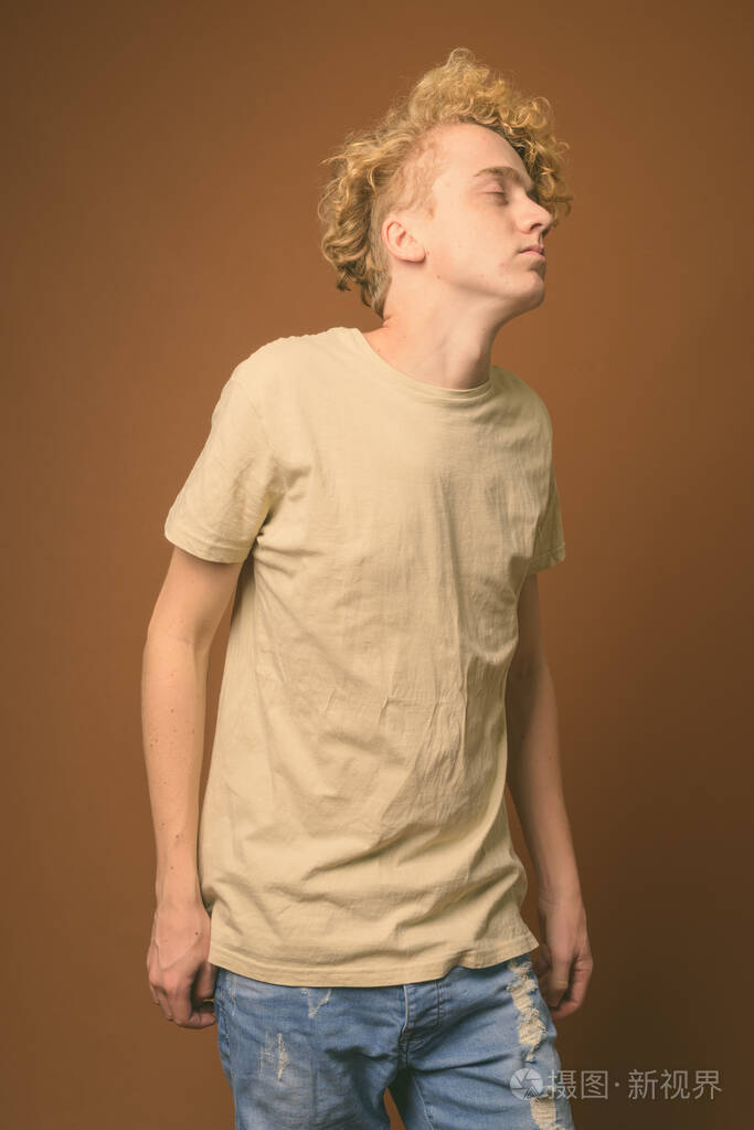 棕色背景下卷发瘦小的年轻人