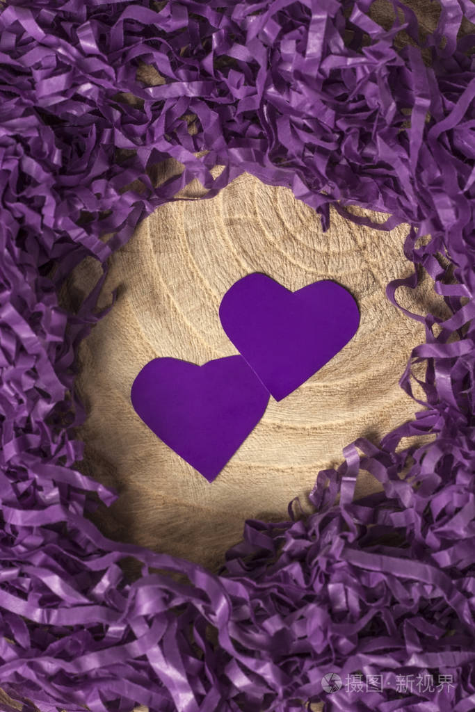 两个漂亮的纸紫色的心里面有一个精致的切碎的纸在木制的背景上