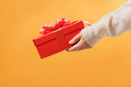 closeup partial view of man in sweater holding red gift box on 