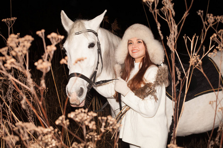 浪漫的女人晚上在户外牵着白马