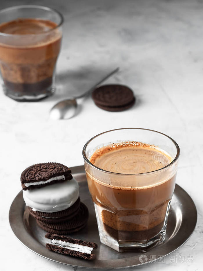 一杯加牛奶的咖啡放在一个金属盘子里,上面放着巧克力饼干.