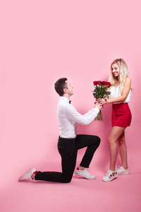 英俊优雅的男人向他美丽的女朋友求婚，送她玫瑰和微笑