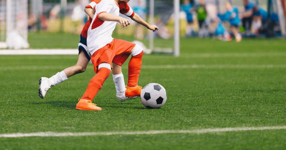 男孩踢足球。足球运动员跑步。五名少年足球运动员决斗。背景是足球场和足球场。