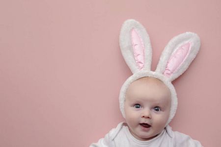 粉色背景上戴着复活节兔子耳朵的可爱小宝宝
