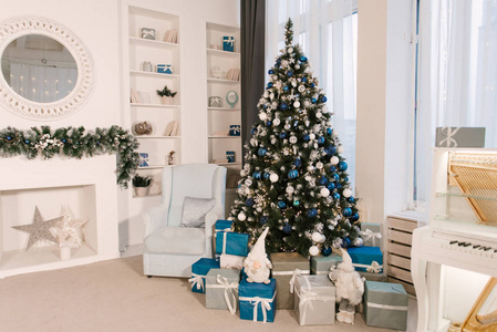 Christmas tree and a chair stands near the fireplace  and other 