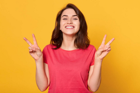 穿着鲜艳的衣服,展示胜利的标志,看起来很开心,直视着摄像机