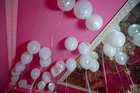 婚礼或儿童生日派对装饰内饰。氦气球红色漂浮。白色的气球飘浮在房间的白色天花板上，以备聚会之用。