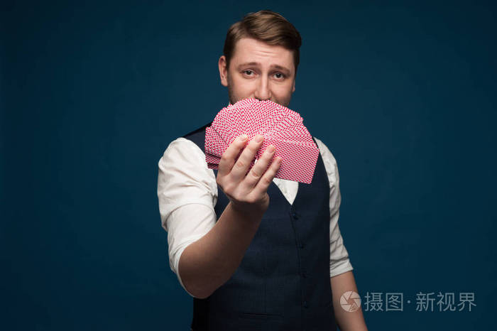 拿着在蓝色背景上展示扑克牌的人