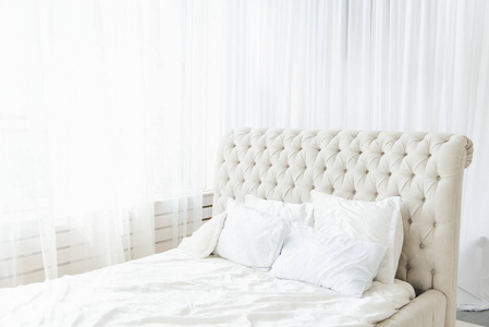 White bedroom with light bed and high headboard, light from the 