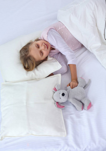 小女孩和玩具泰迪熊睡在床上。