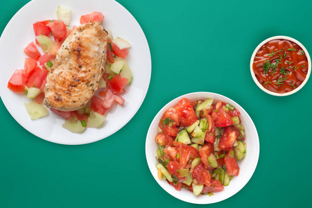 Grilled chicken breast with tomato salad, cucumbers and onions. 