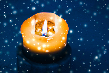 在品牌上的星星黄色节日蜡烛在蓝色闪闪发光的雪地背景上,鲁迅照片