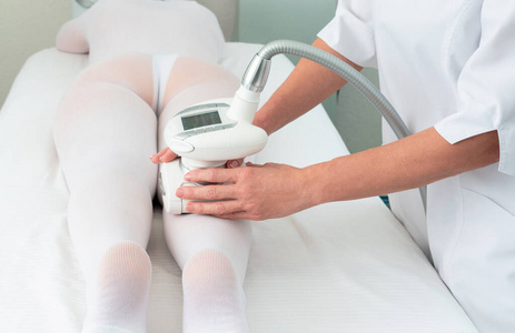 一位身着特殊白色套装的女士在一家温泉沙龙接受腿部减肥按摩。液化石油气LPG与临床上的塑形治疗。