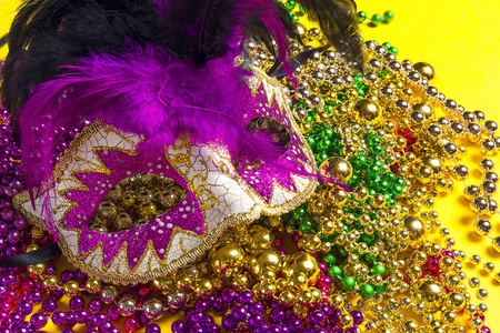 Festive Carnival masks and beads on yellow background. 