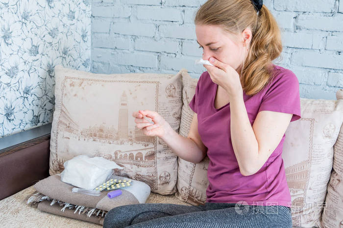 一个感冒的女人看了看体温计.流感和病毒性疾病引起的高烧和头痛.