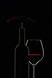 Bottle and glasses of red wine on a black background. 