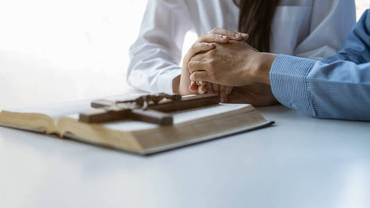 基督教妇女双手合十在圣经和木十字架上祈祷.