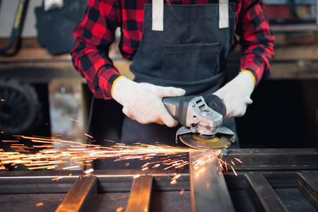 工人在工厂里用手电锯片打磨钢结构,产生火花照片