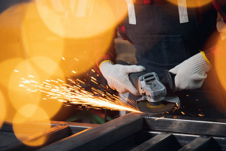 工人在工厂里用手电锯片打磨钢结构,产生火花照片