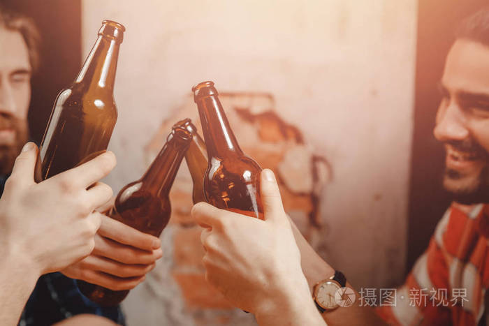 酒杯和一瓶黑啤酒朋友们在吧台上碰杯