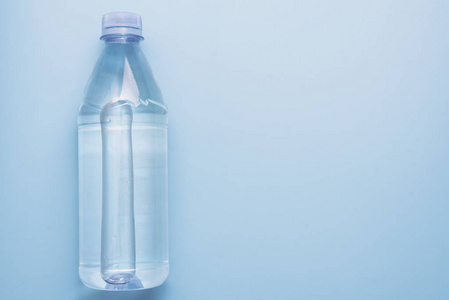 蓝色背景塑料水瓶，带复印空间，俯视图