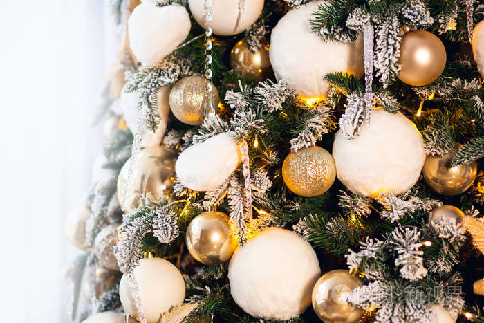 圣诞背景为浅色和金色，新年树装饰有球和人造雪照明