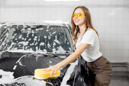 洗车服务.工人美女用黄色海绵清洗汽车黑色泡沫照片