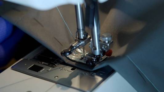 Closeup of sewing machine needle rapidly moves up and down. 