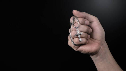 手持十字架吊坠和项链的特写图片,代表为上帝或耶稣祈祷,感谢上帝给予