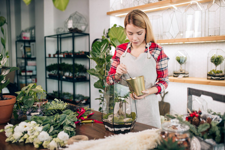 年轻的女花匠照看和照顾植物照片