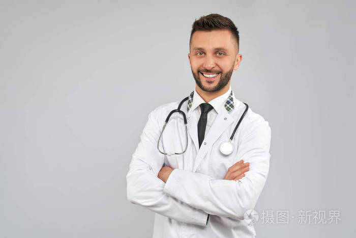 微笑的医生拿着担架镜隔离在灰色。