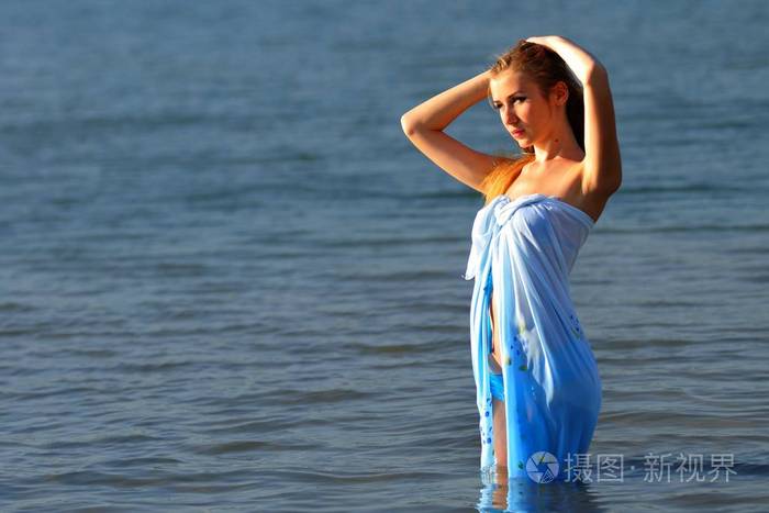 穿着比基尼的年轻女子站在阳光下的水中