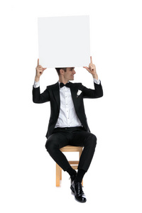 young elegant man holding empty board above head 