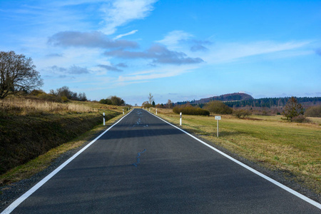 孤独的道路穿过绿色的风景,蓝天和阳光在罗恩,德国照片