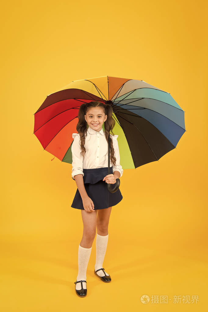 黄色背景下,小孩举着五颜六色的雨伞迎接秋雨.