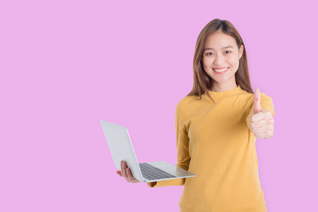 美丽的亚洲年轻女子拿着笔记本电脑，微笑着伸出大拇指