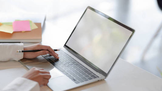 Cropped shot of businesswoman typing on blank screen laptop with