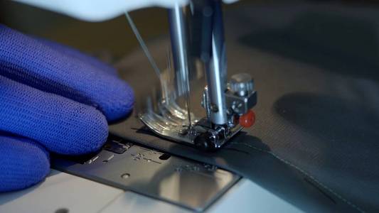 Closeup of sewing machine needle rapidly moves up and down. 