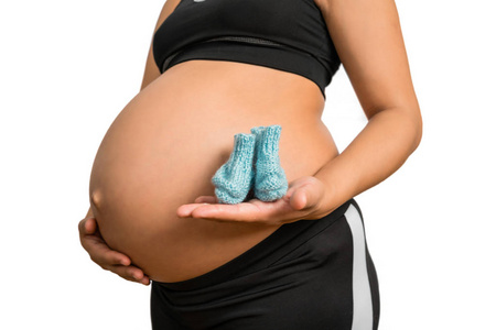 Pregnant woman holding baby socks on belly. 