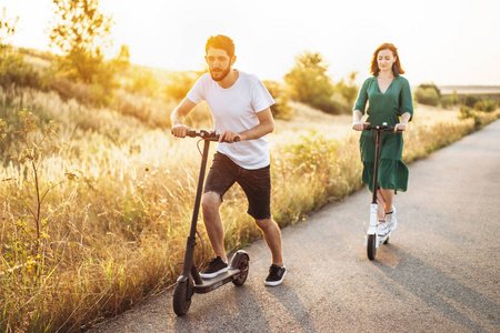 Young couple on vacation having fun driving electric scooter on 