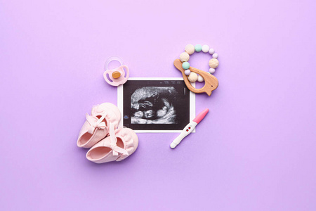 怀孕测试，婴儿靴，超声波图像，玩具和奶嘴的彩色背景