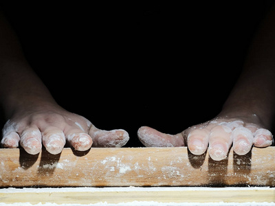 一位手拿面粉的厨师正准备在黑色背景下做饭照片