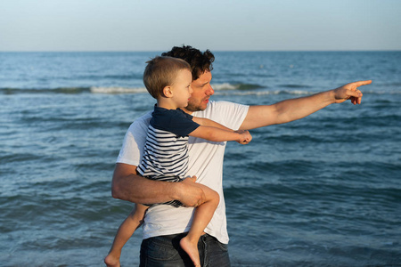 Young Caucasian dad with little son walk warm summer day along t