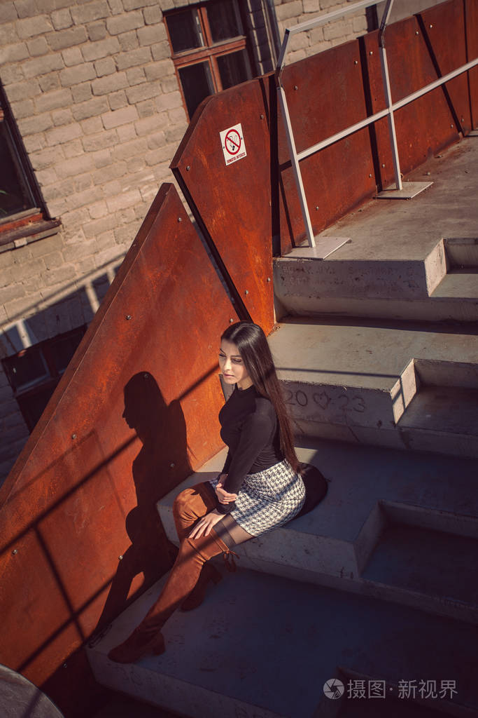 时髦的女模特坐在大楼的台阶上摆姿势