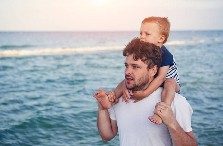 Young Caucasian dad with little son walk warm summer day along t