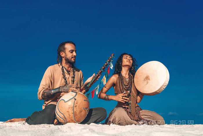 beautifulyoungcoupleplayingethnicalmusicwithshamandrums