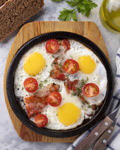 煎鸡蛋，培根和西红柿。美味的煎锅早餐。俯视图
